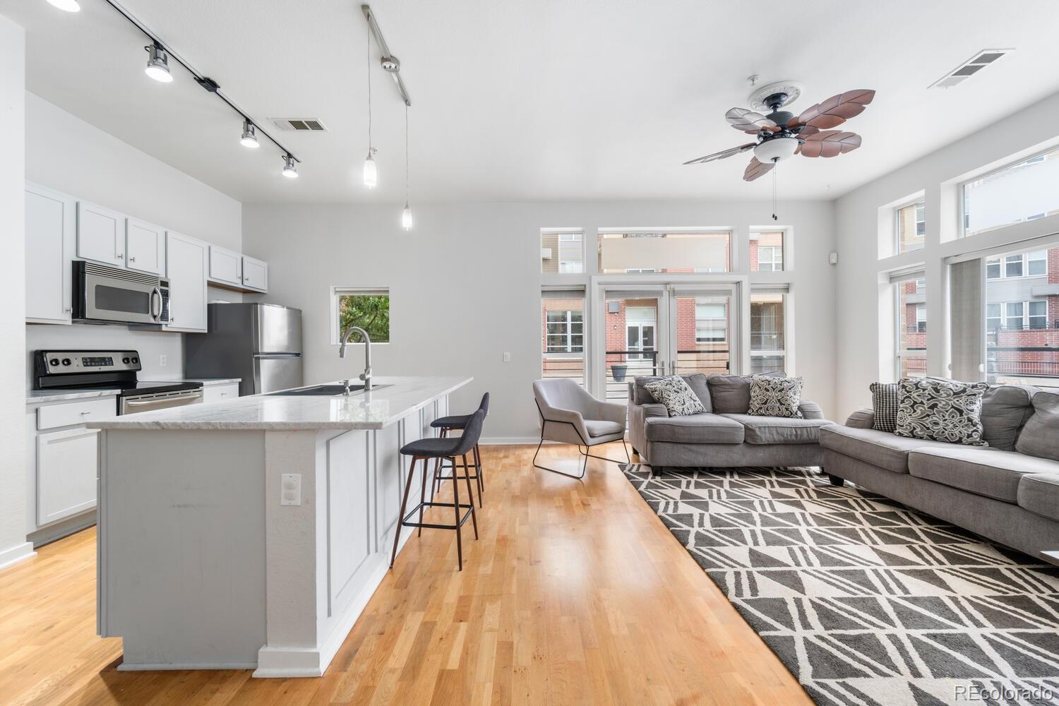 a living room with stainless steel appliances furniture a rug kitchen view and a chandelier