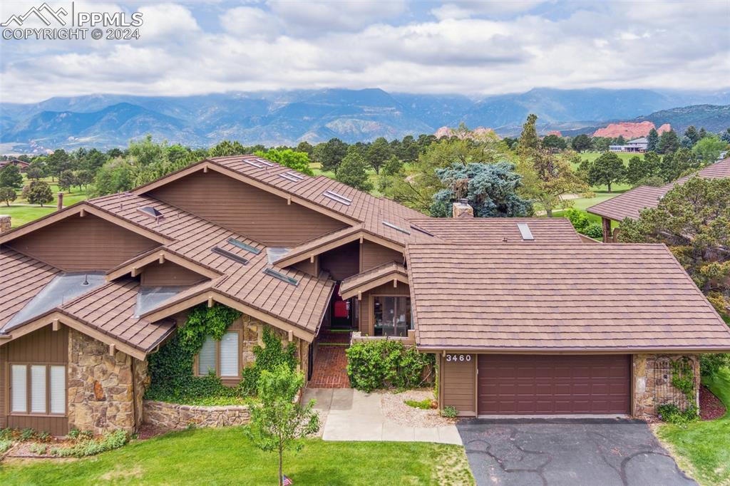 View of front facade featuring a garage, a mountain view, and a front lawn