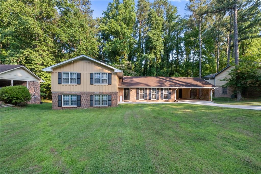 a view of a house with a big yard and large trees