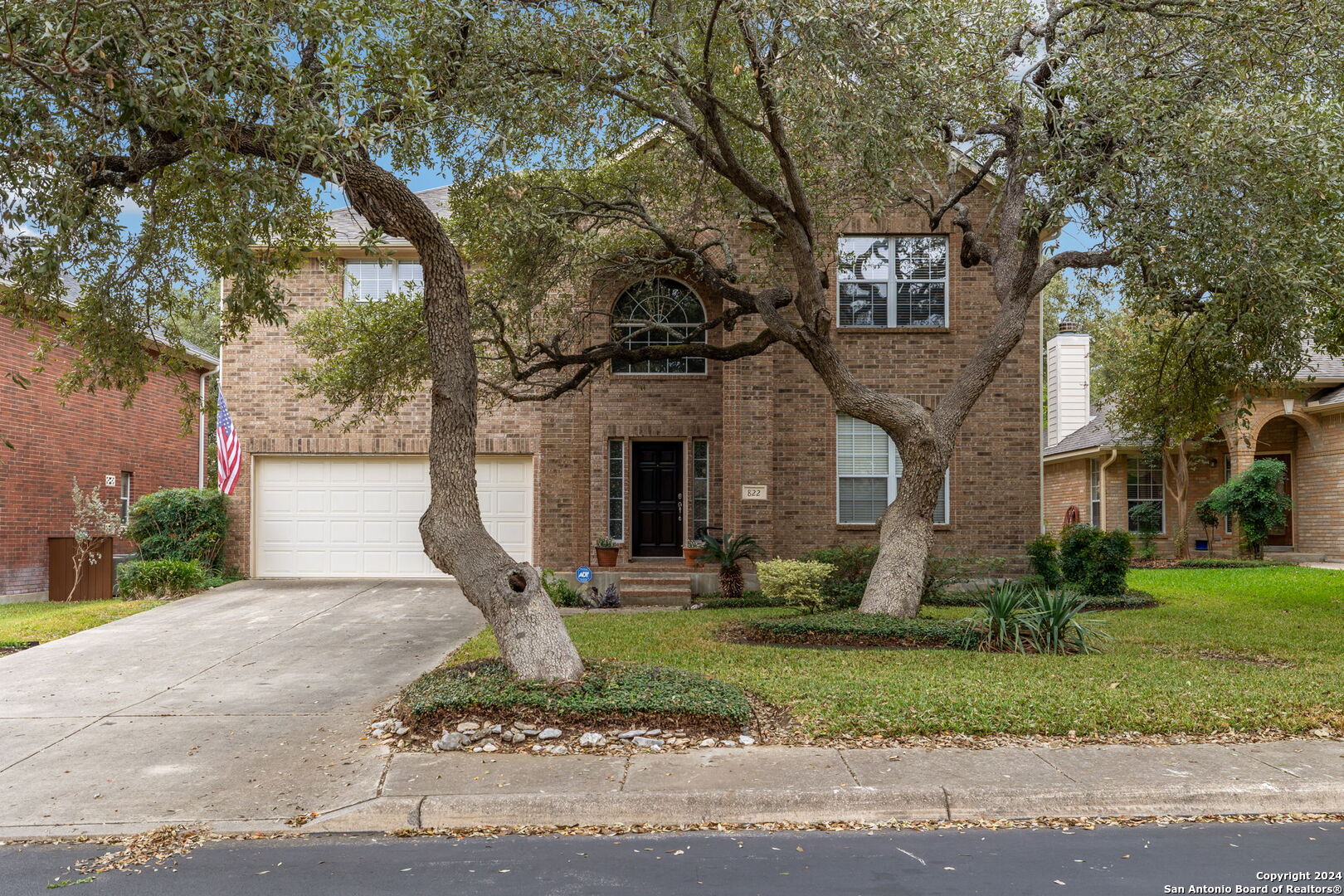 a front view of a house with garden and trees