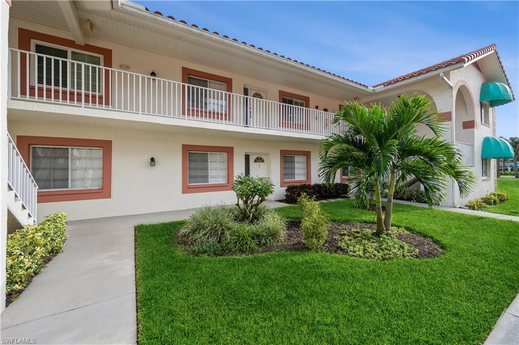 View of front of property featuring a balcony and a front lawn