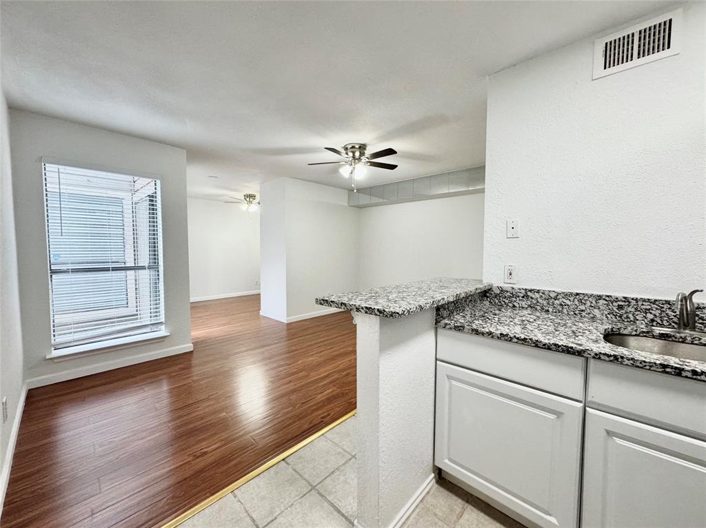 a kitchen with granite countertop a stove and white cabinets with wooden floor