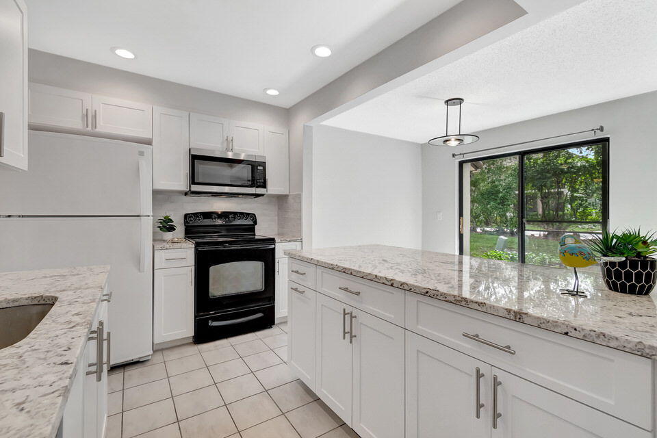 a kitchen with granite countertop a stove a sink and a refrigerator