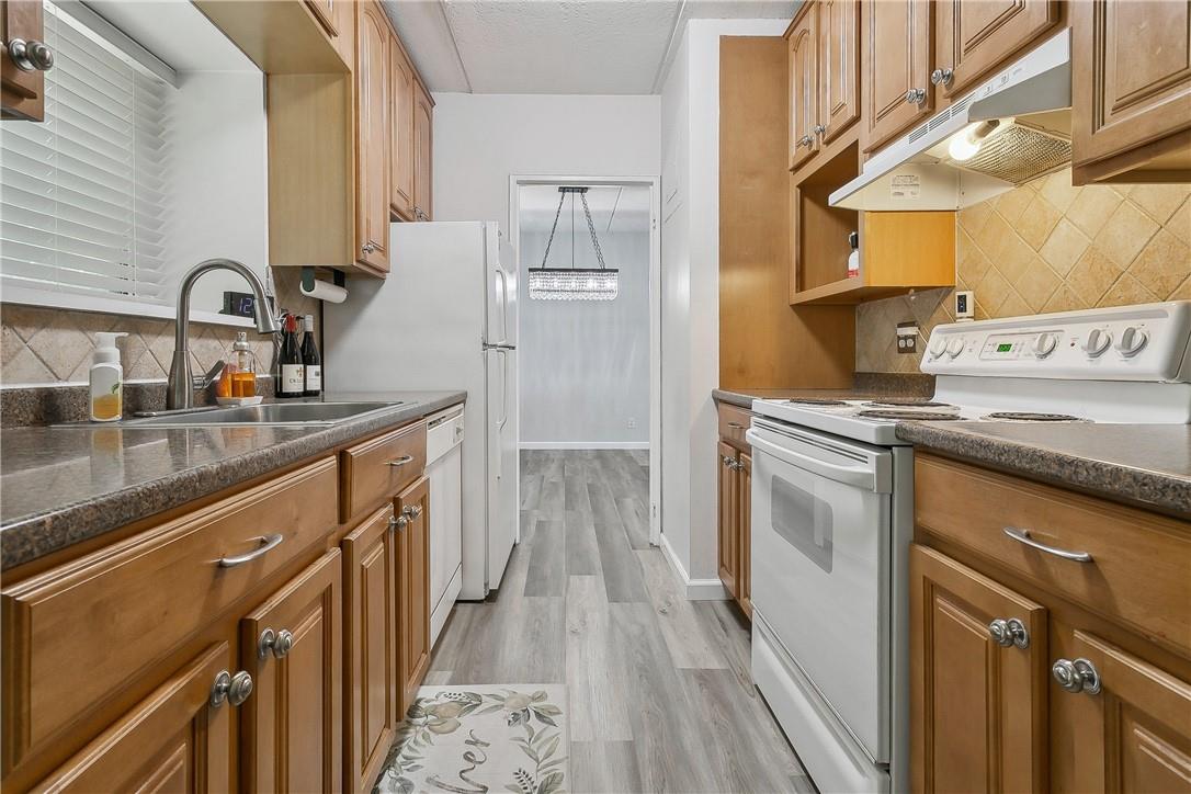 Kitchen with sink, backsplash, light hardwood / wood-style floors, and white electric range oven