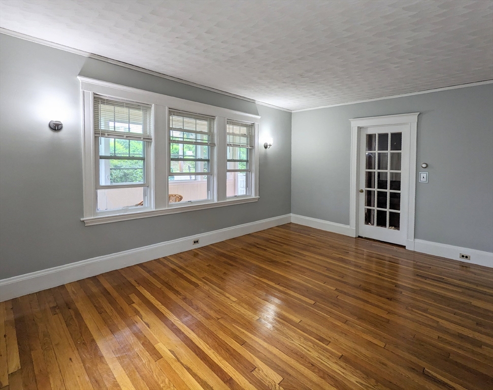 a view of an empty room with wooden floor and window