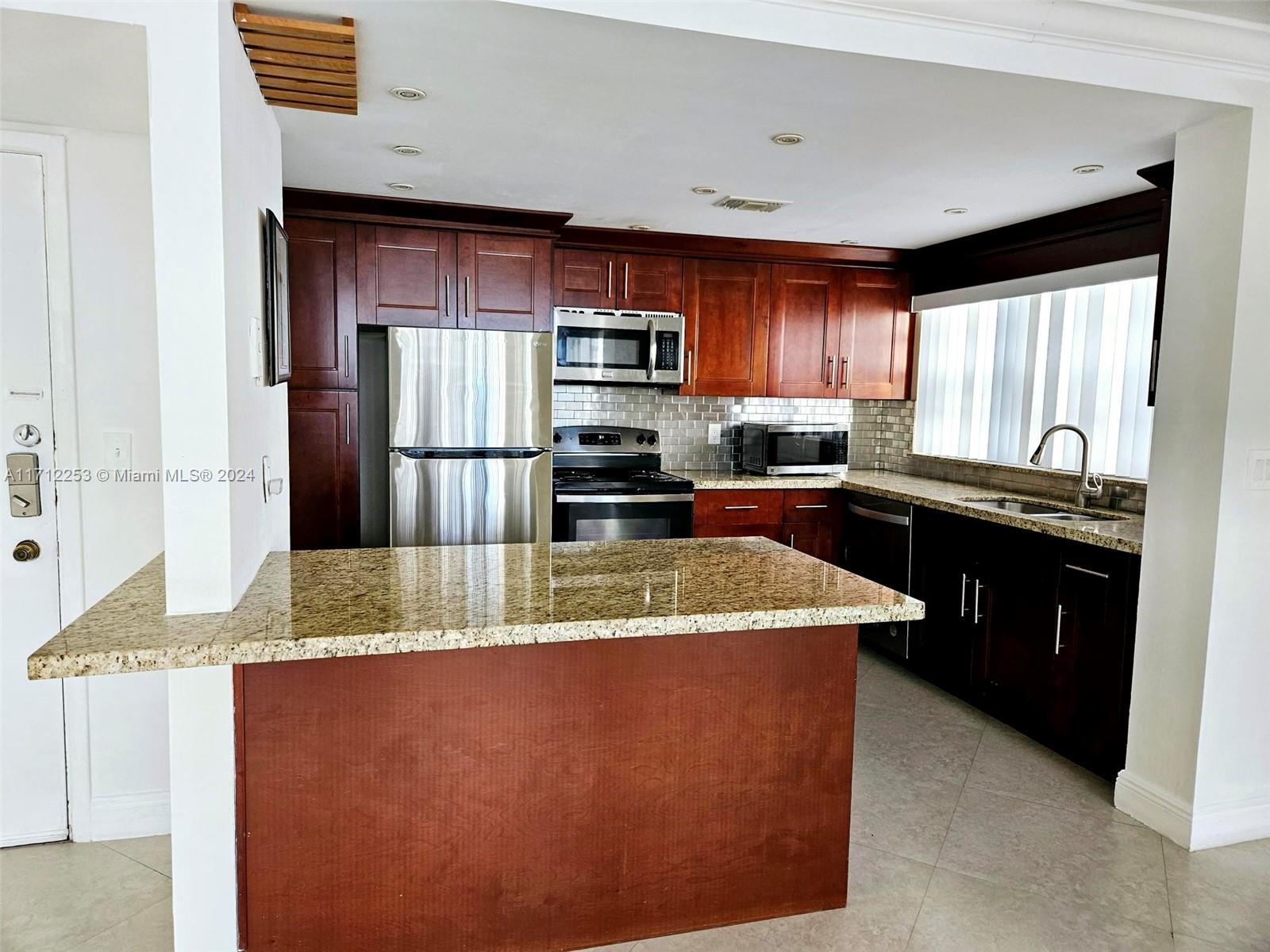 a kitchen with stainless steel appliances granite countertop a sink a stove and a refrigerator