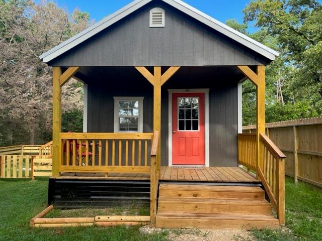 a view of front door of house with stairs yard and wooden fence