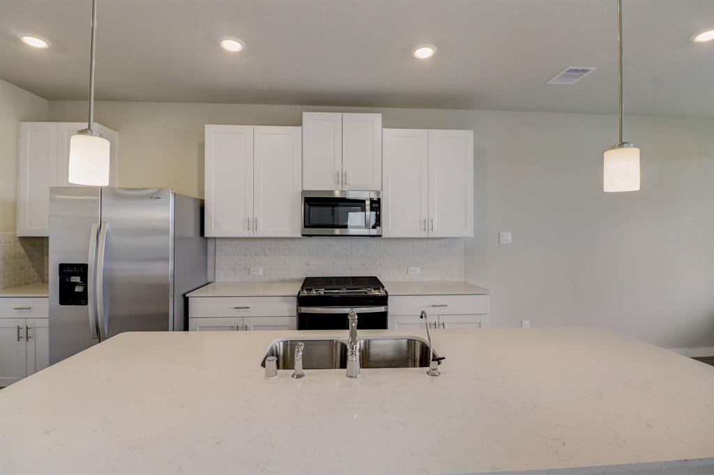 a kitchen with kitchen island a counter space a sink appliances and cabinets