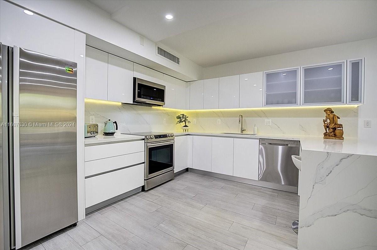 a kitchen with stainless steel appliances a white cabinet and a stove top oven