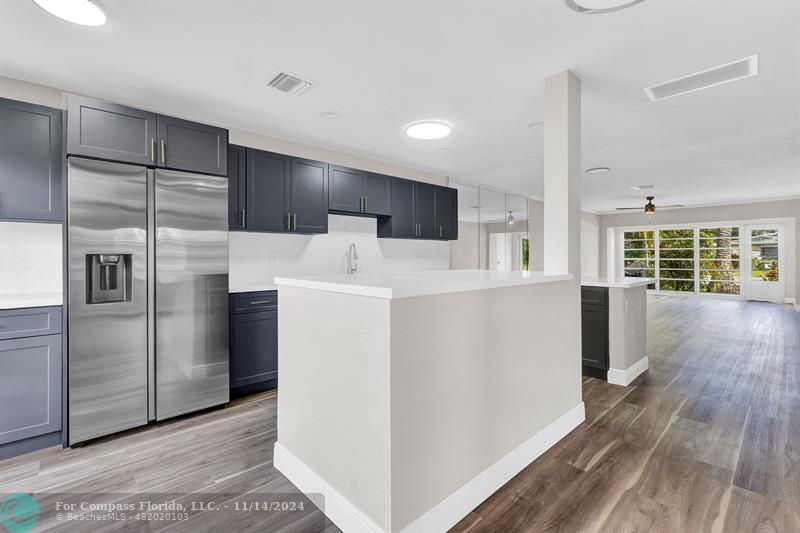 a view of kitchen with stainless steel appliances wooden floor and window