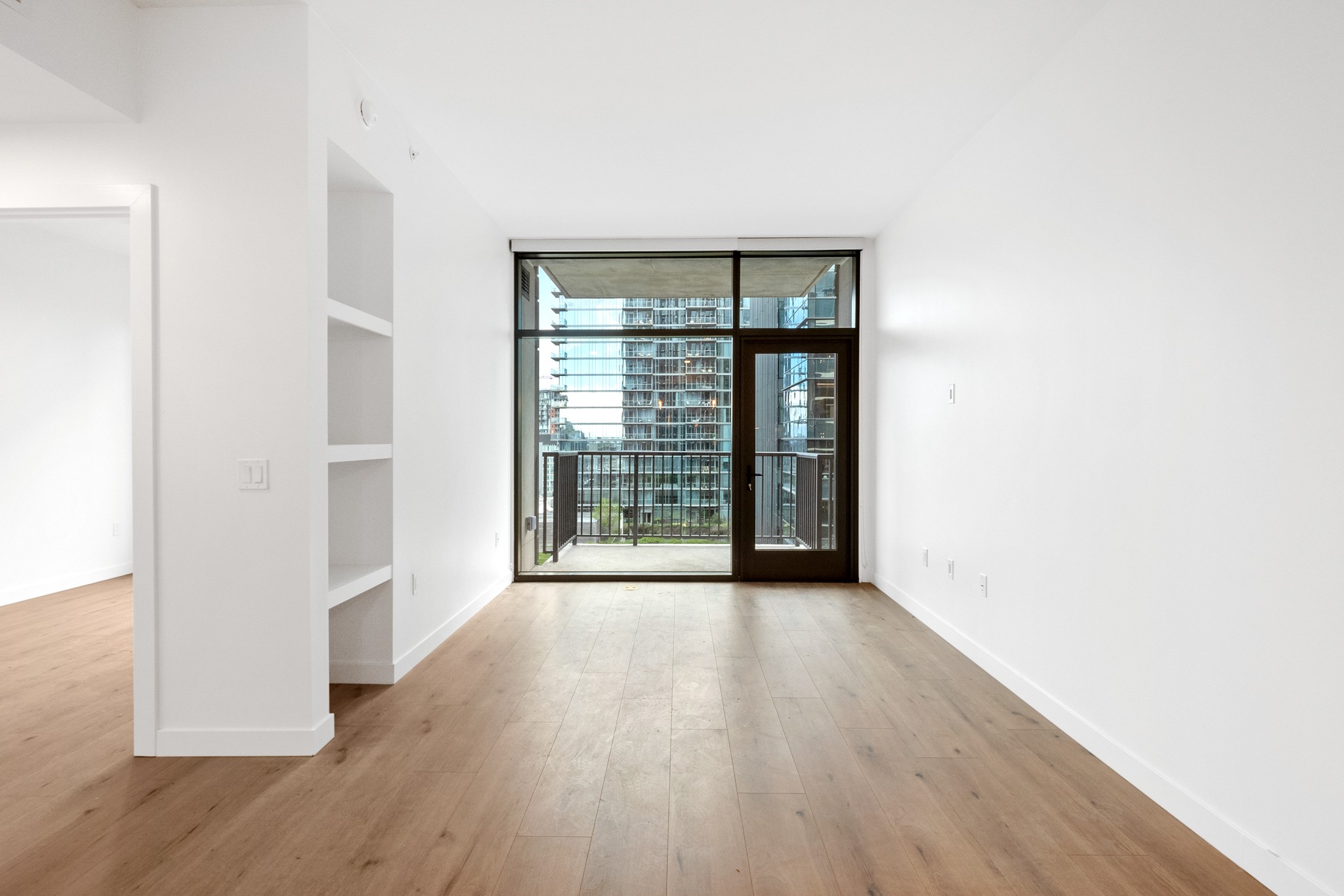 a view of an empty room with wooden floor and a window