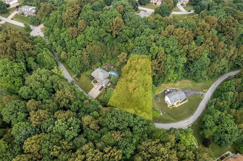 an aerial view of residential house with outdoor space and trees all around