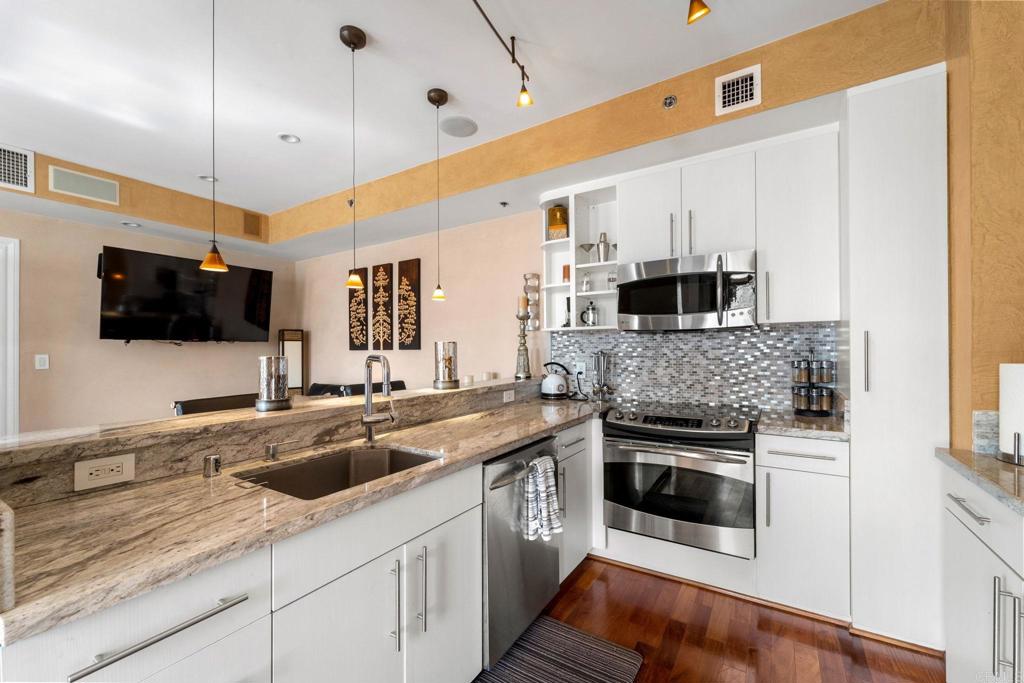 a kitchen with stainless steel appliances granite countertop a sink a stove a microwave and wooden cabinets