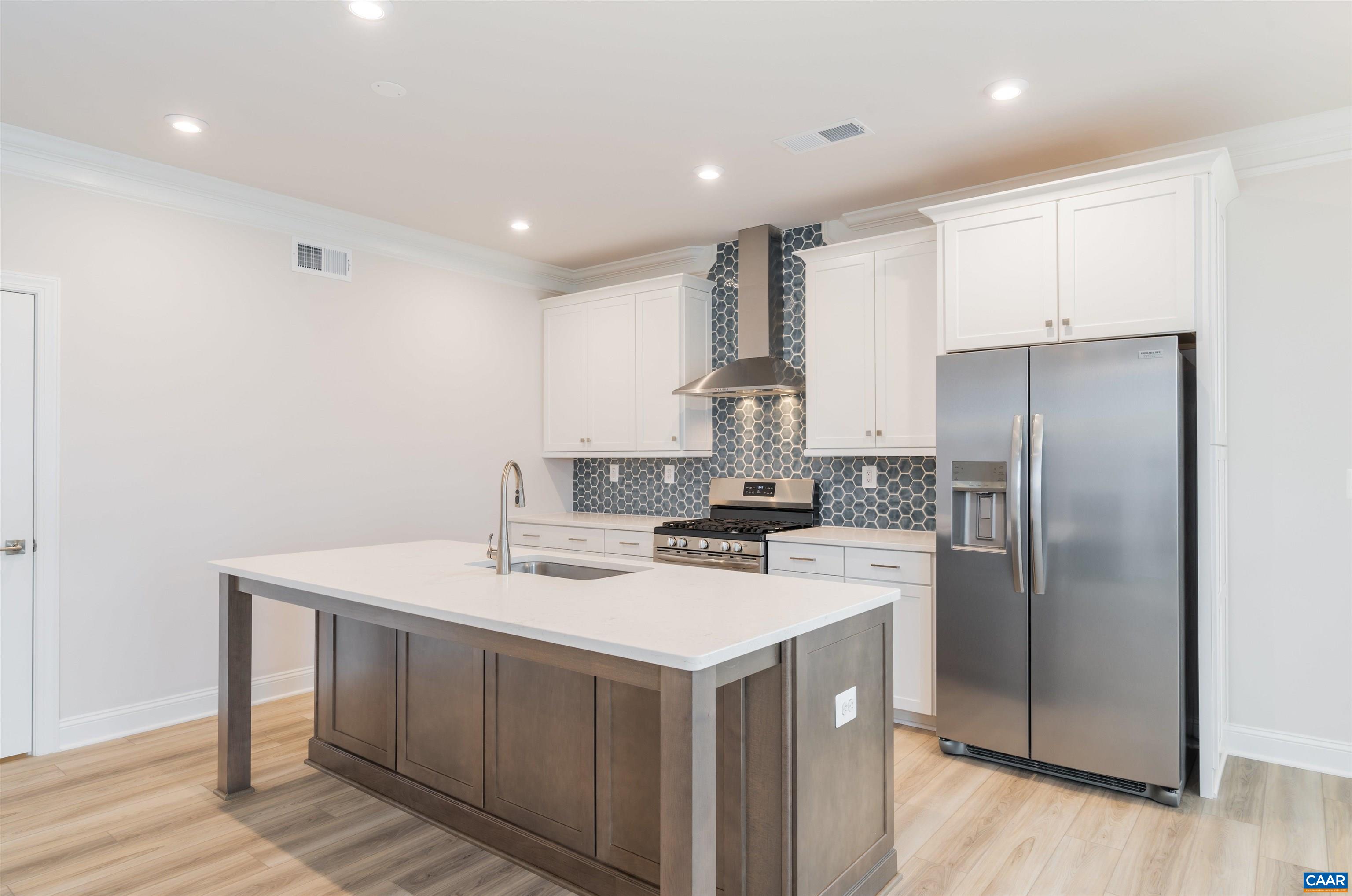 a kitchen with a sink a refrigerator a stove and white cabinets with wooden floor