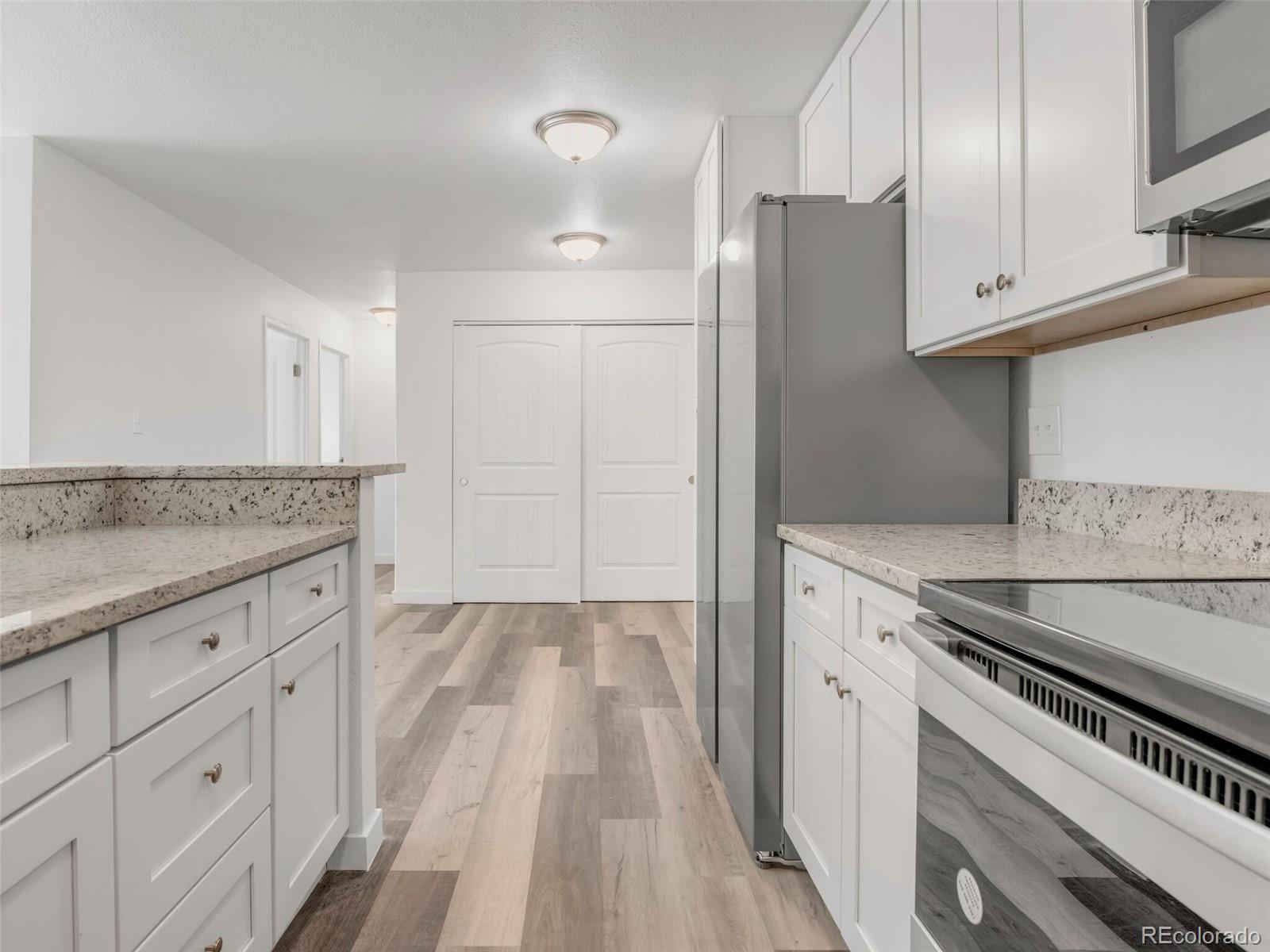 a kitchen with granite countertop white cabinets and stainless steel appliances