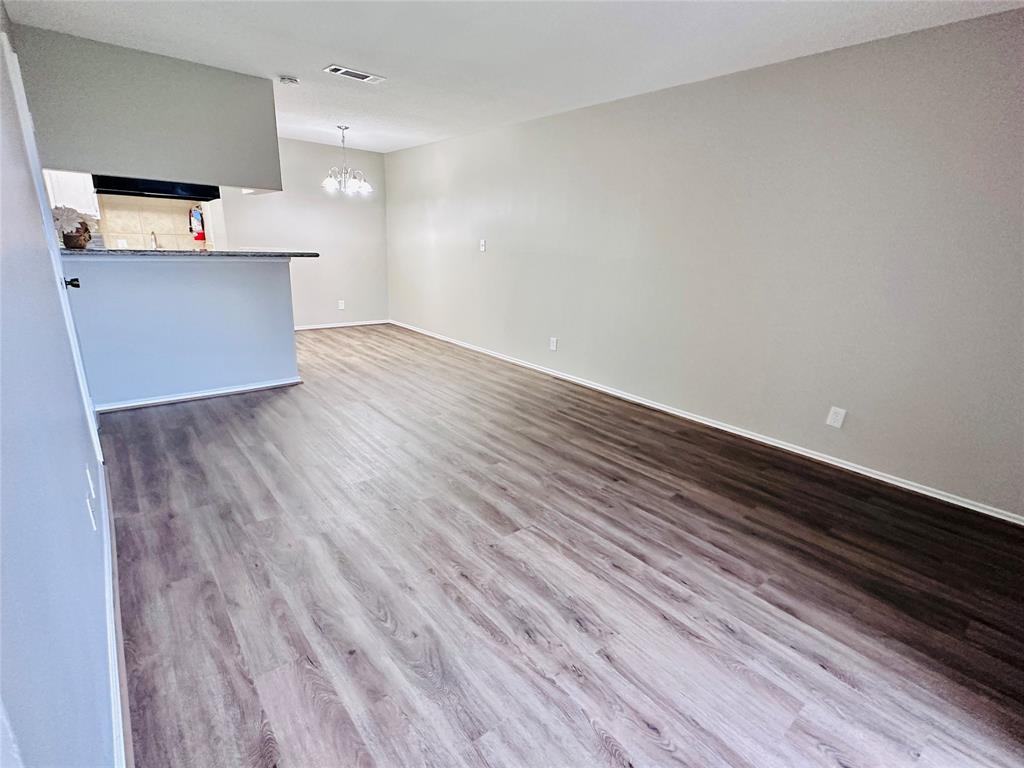 a view of kitchen and empty room with wooden floor