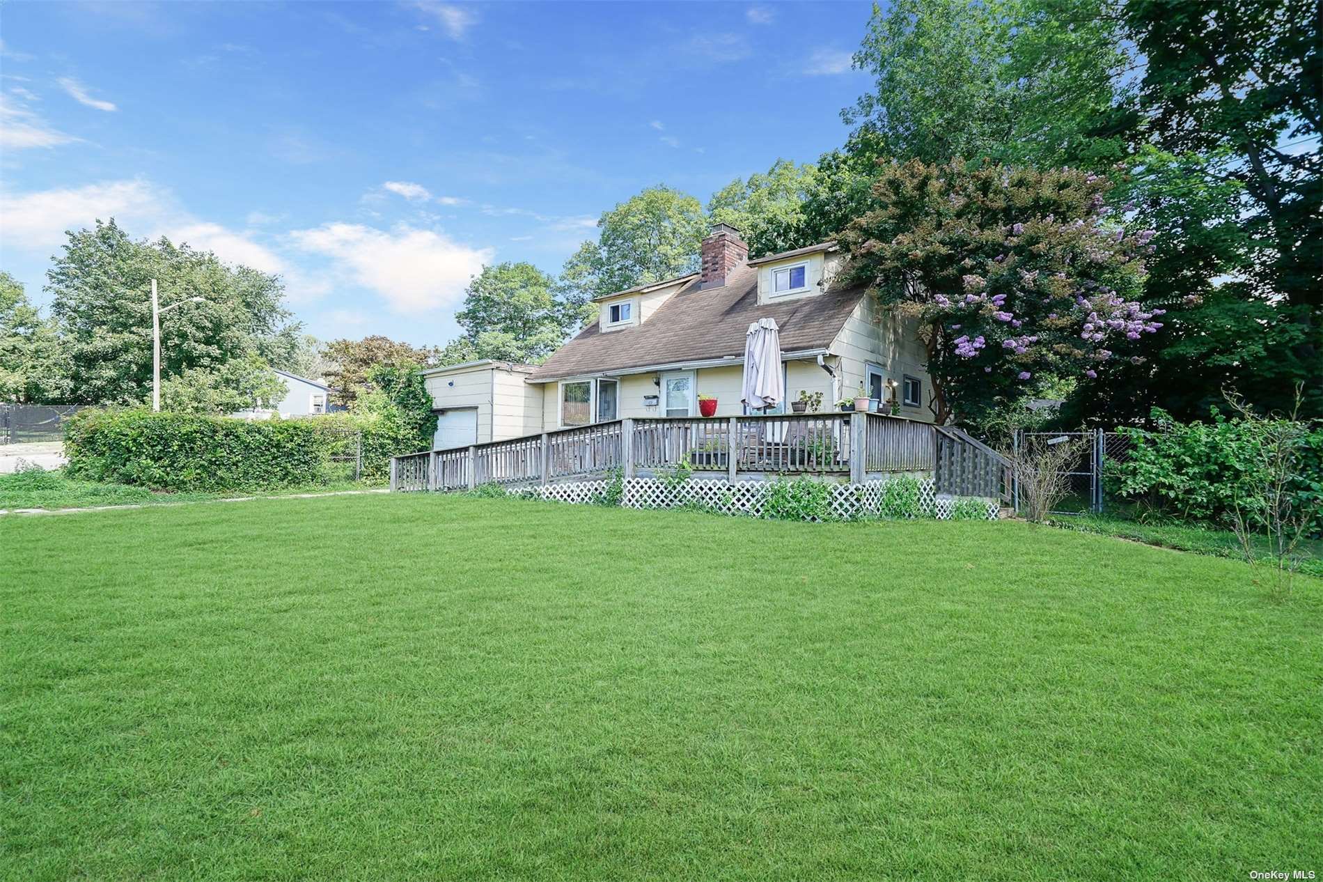 a view of a house with a big yard potted plants and large tree