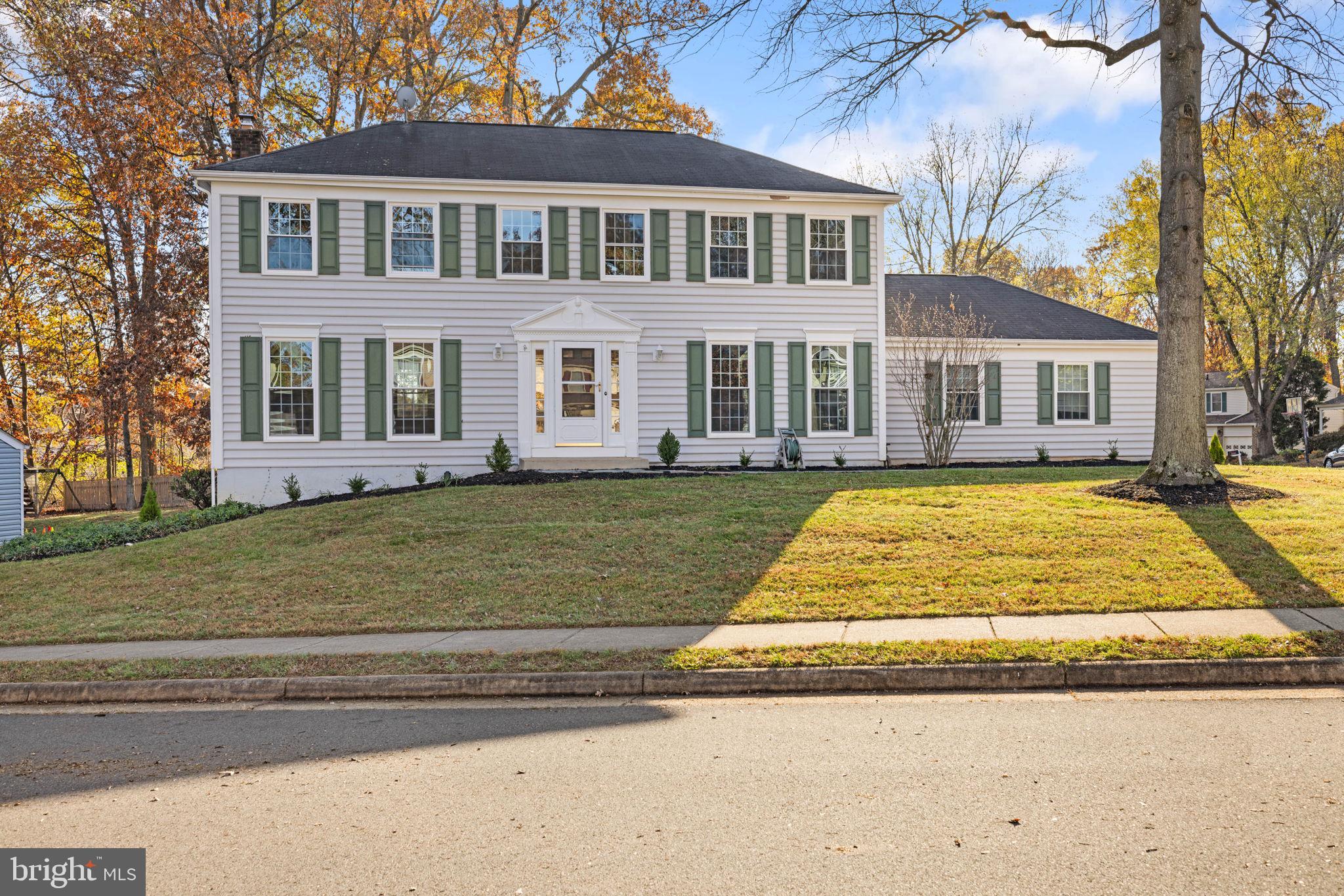 a view of a yard in front of a brick house with large windows