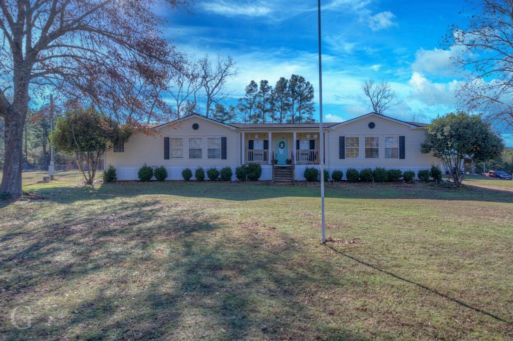 a view of house in front of a big yard with large trees