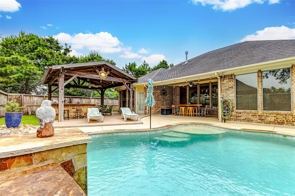 Welcome to your backyard oasis complete with covered porch, covered patio with outdoor kitchen and pool with a waterfall.