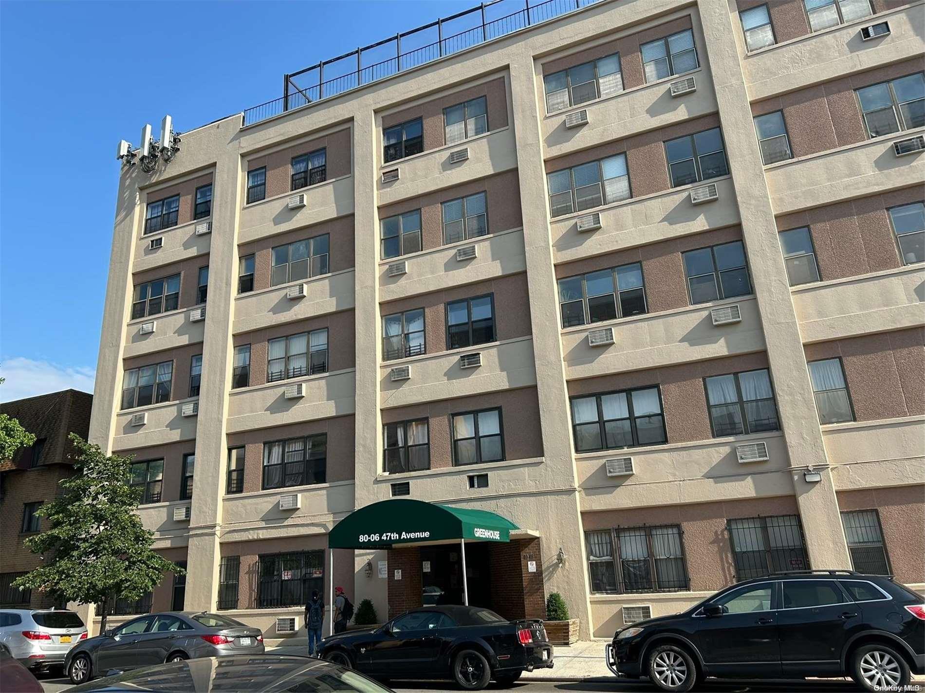 a front view of a building with lot of cars parked