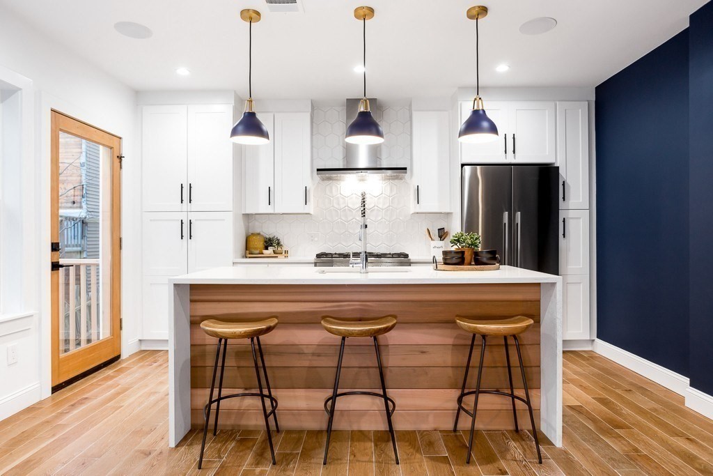 a kitchen with stainless steel appliances a dining table chairs and wooden floor