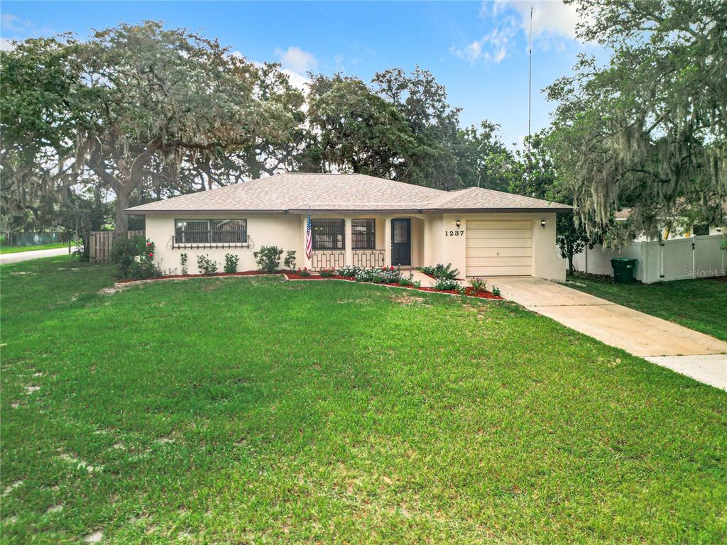 a front view of a house with a garden and trees