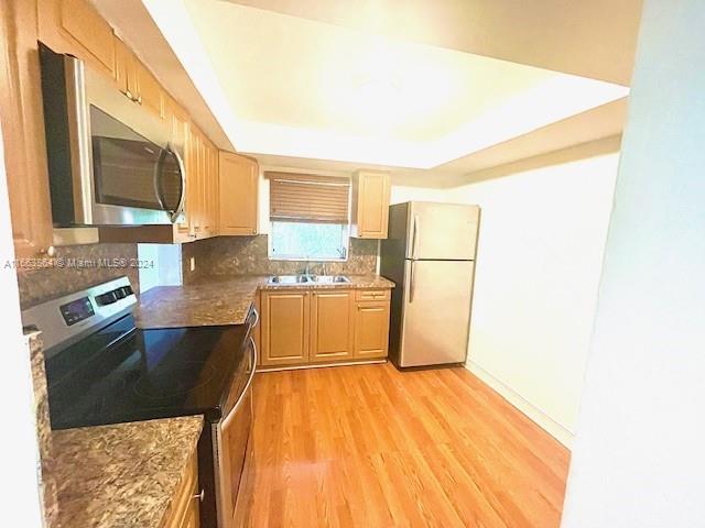 a kitchen with granite countertop a refrigerator a sink and dishwasher with wooden floor