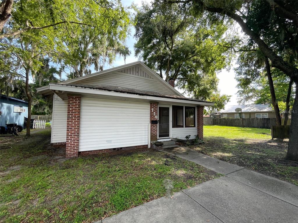 a view of a house with a yard and large tree