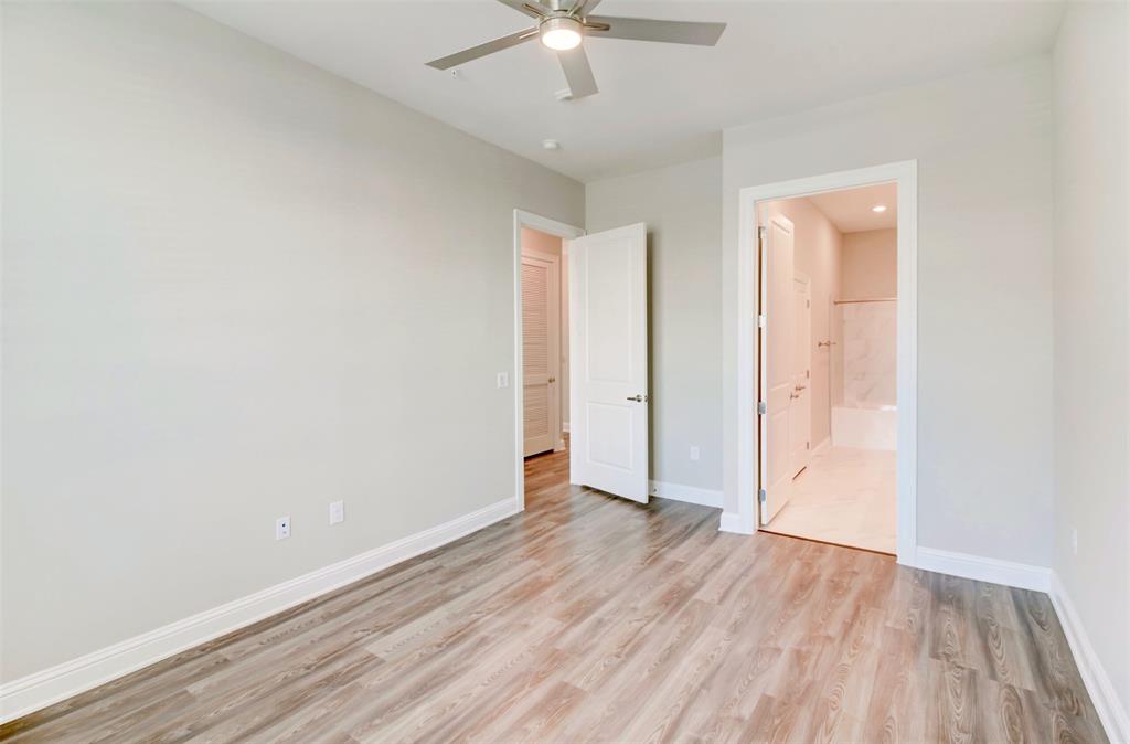 an empty room with wooden floor and fan