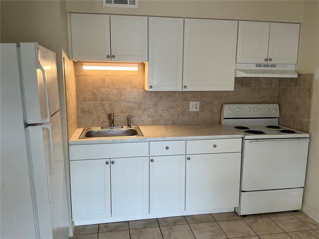 a kitchen with white cabinets and white appliances