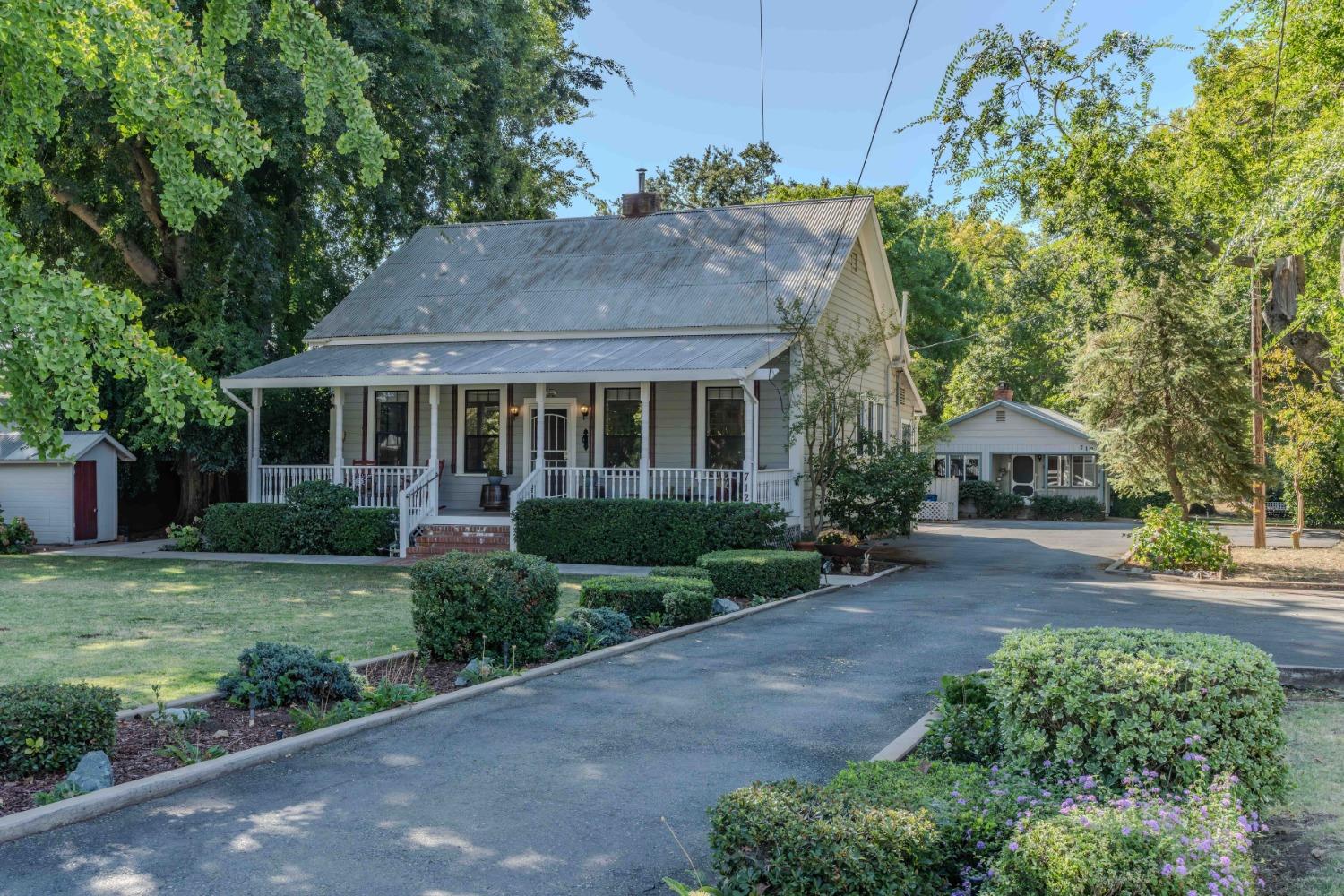 a front view of a house with a garden and trees