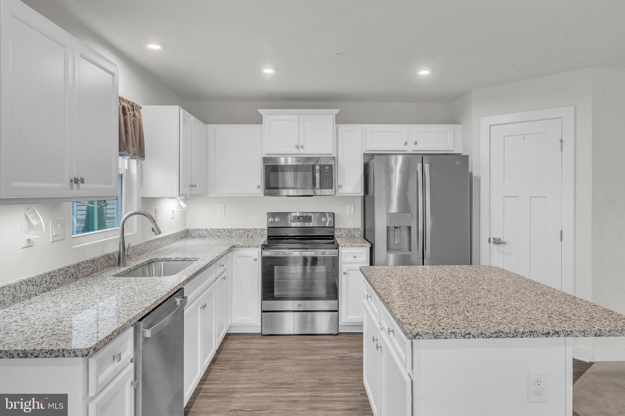 a kitchen with kitchen island granite countertop a sink stove refrigerator and cabinets