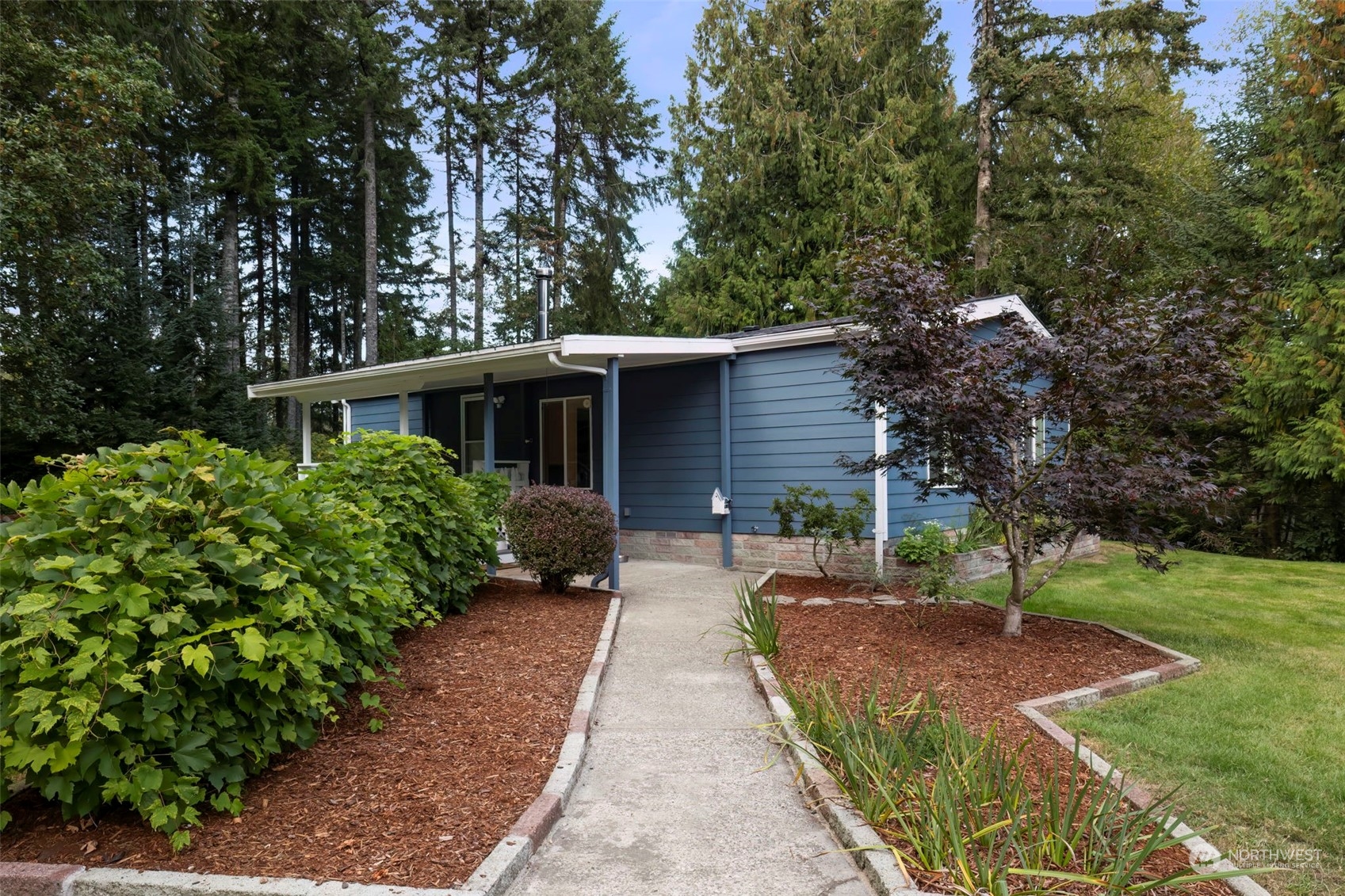 a front view of a house with a garden and trees