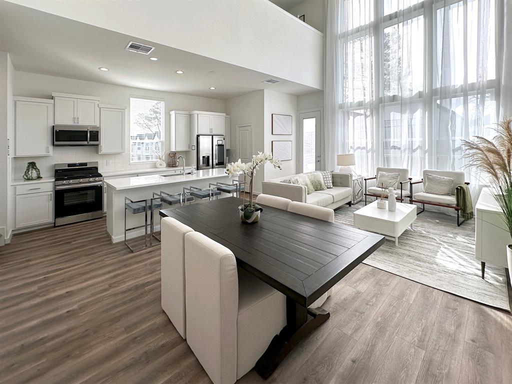 a living room with stainless steel appliances granite countertop a couch wooden floor and a view of living room