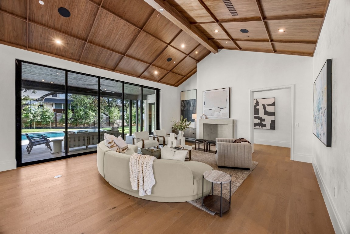 a living room with furniture large windows and wooden floor