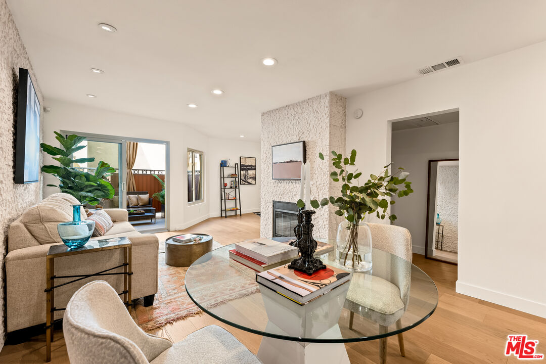 a living room with furniture couches and a dining table with wooden floor