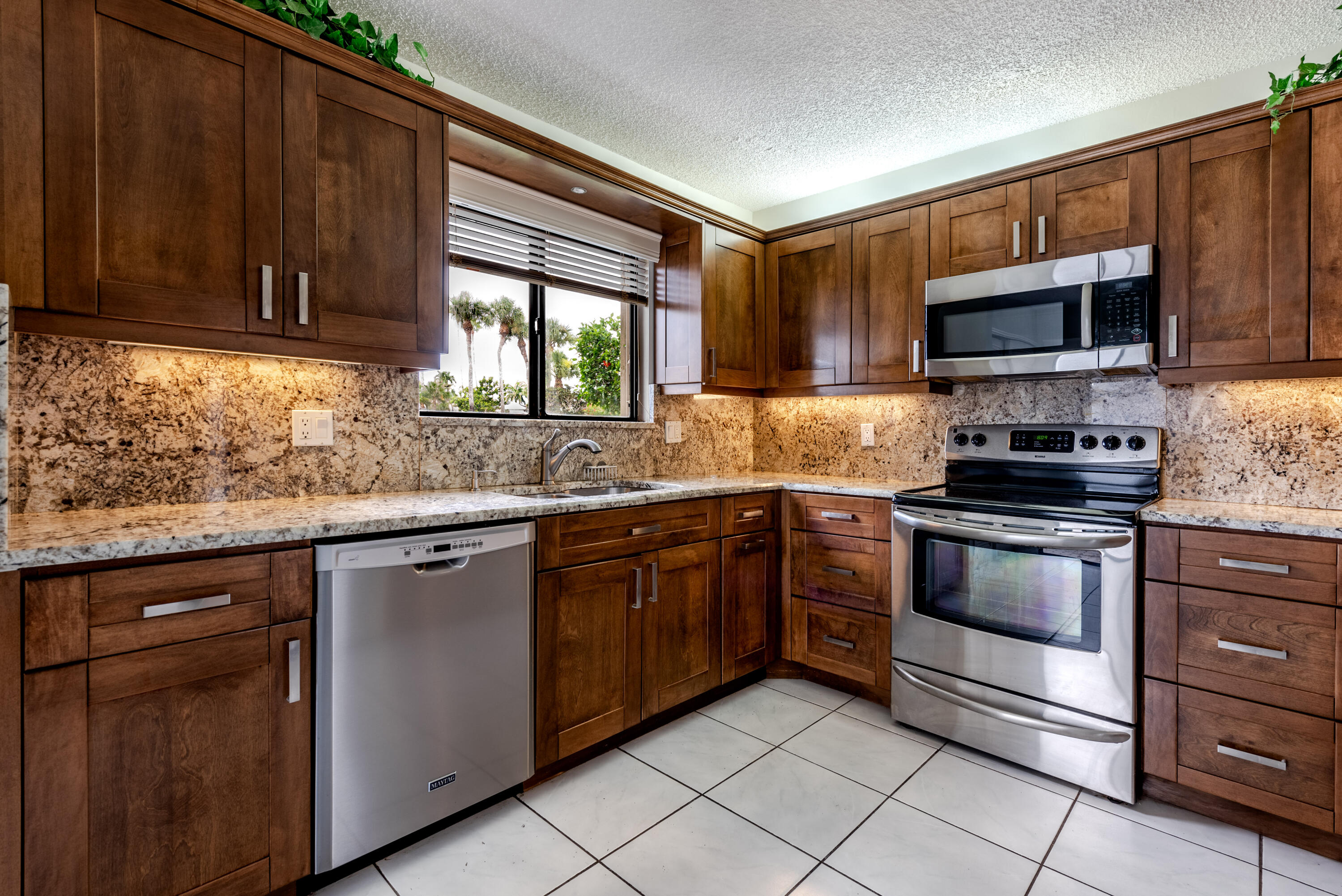 a kitchen with stainless steel appliances granite countertop wooden cabinets a stove top oven a sink and dishwasher