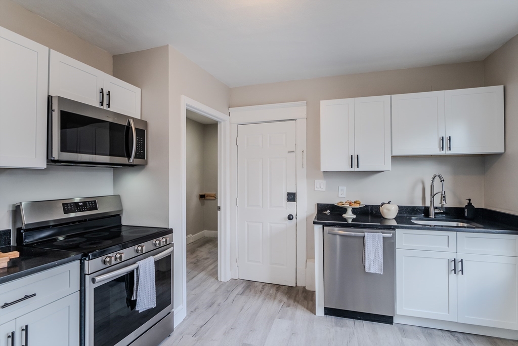 a kitchen with cabinets stainless steel appliances and wooden floor