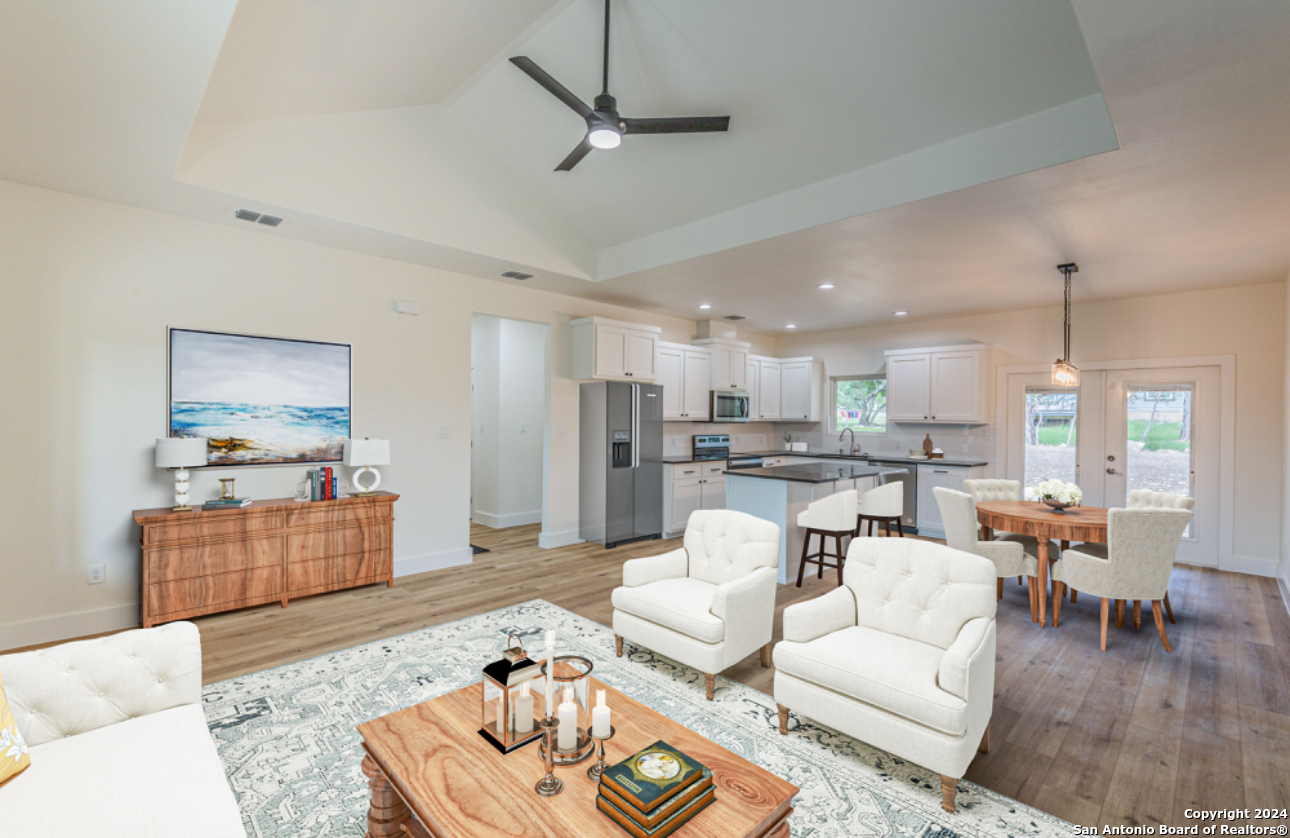 a living room with furniture kitchen view and a wooden floor