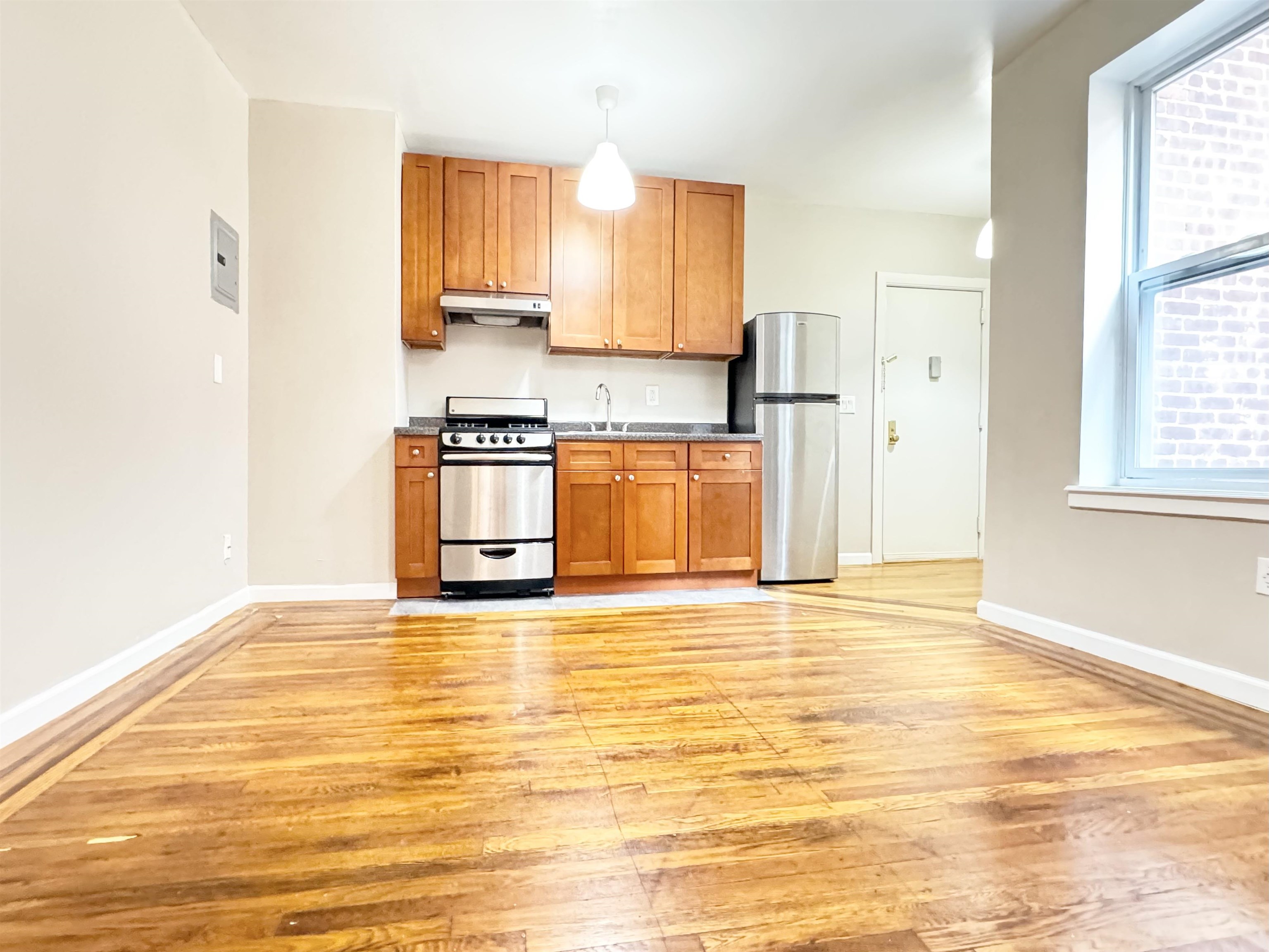 a view of a kitchen with wooden floor and a window