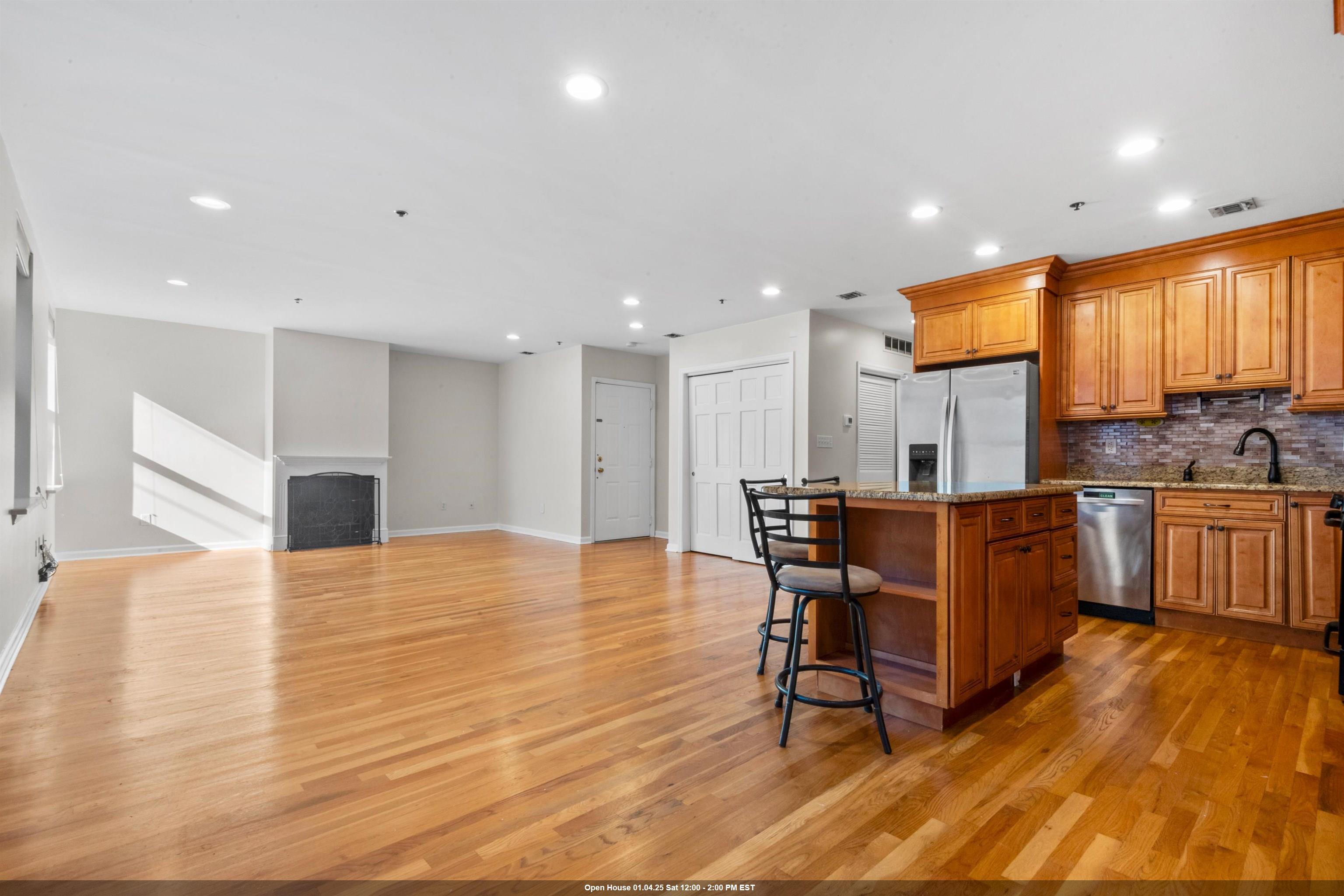 a view of a kitchen with kitchen island dining table wooden floor and stainless steel appliances