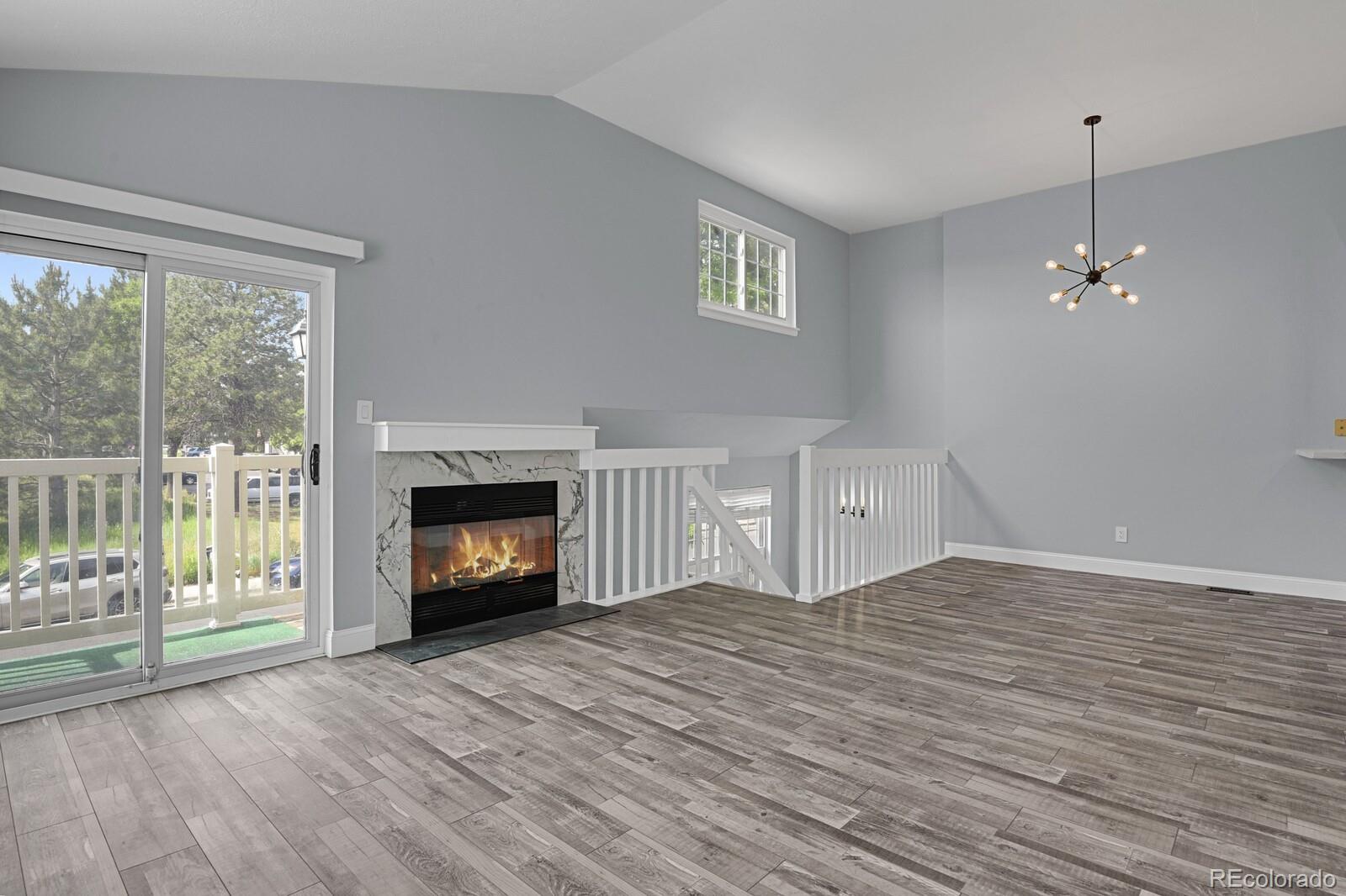 a view of an empty room with wooden floor fireplace and a window