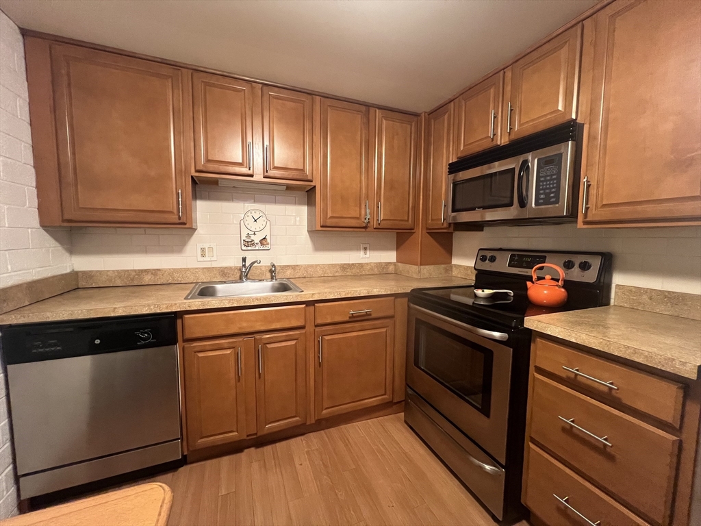 a kitchen with granite countertop wooden cabinets stainless steel appliances and a sink