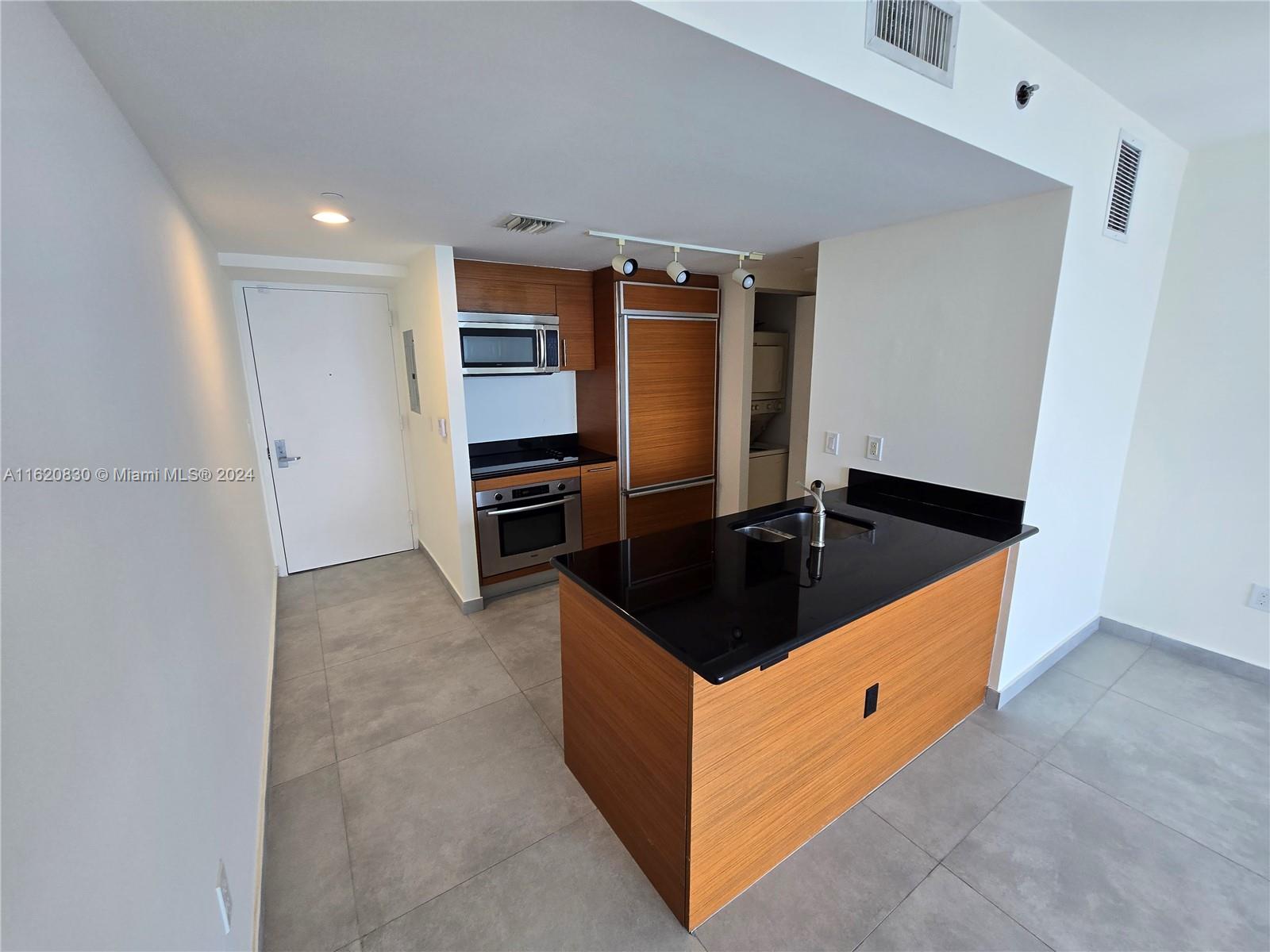 a kitchen with granite countertop a sink refrigerator and cabinets