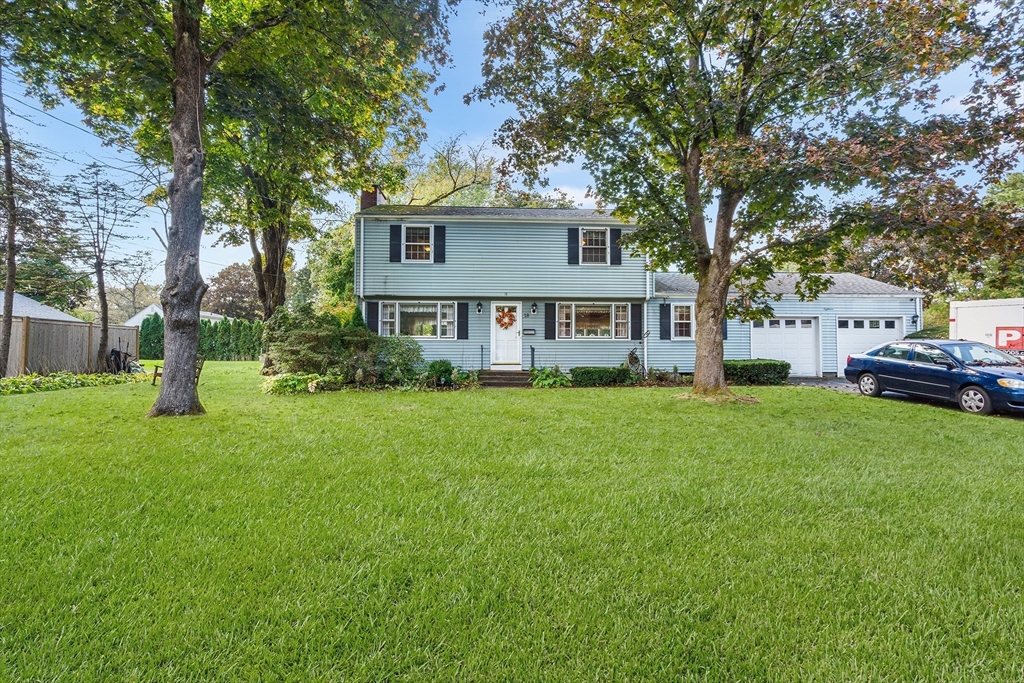 a front view of a house with a garden and trees