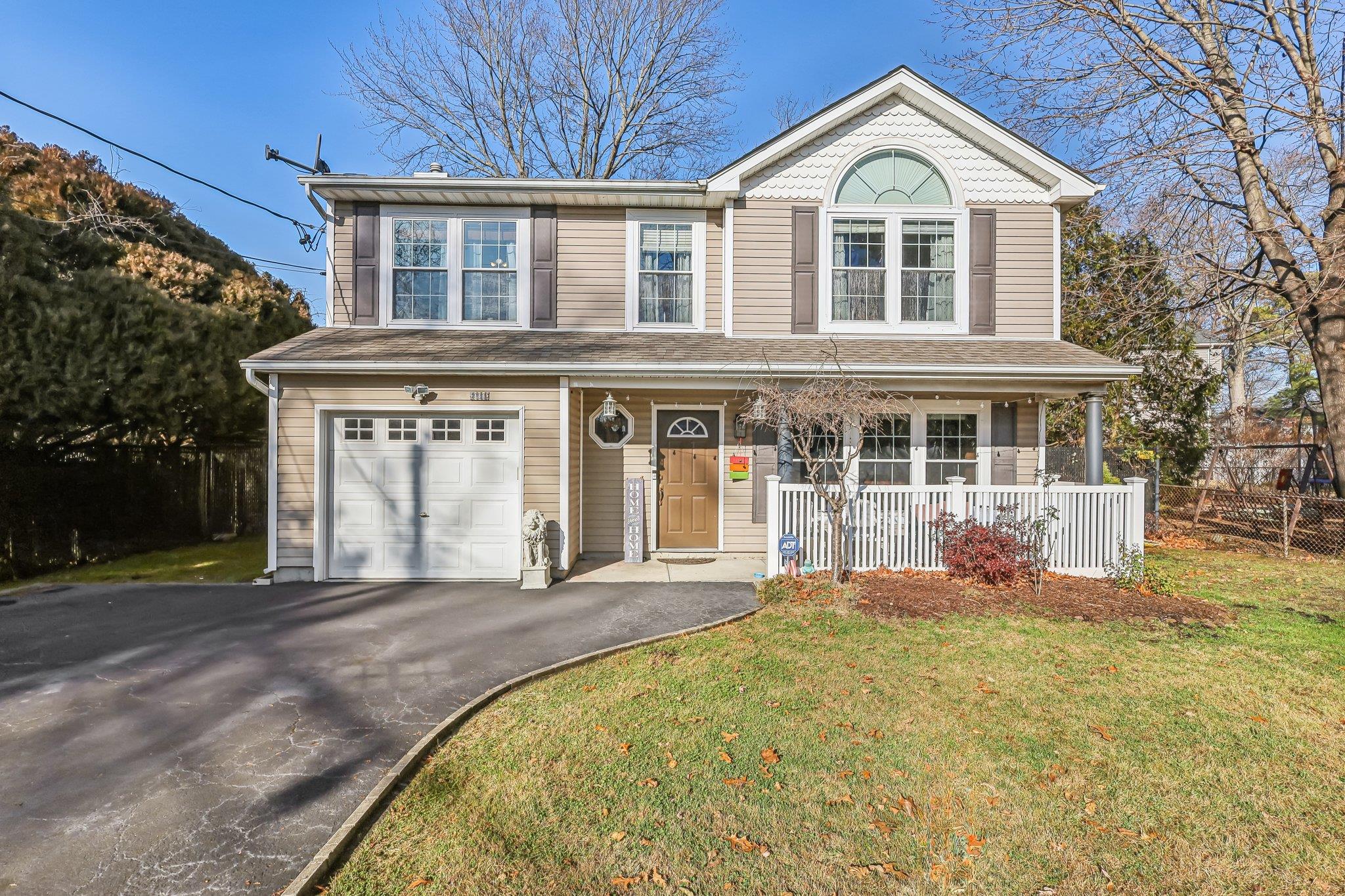 View of front property featuring a porch, a garage, and a front lawn