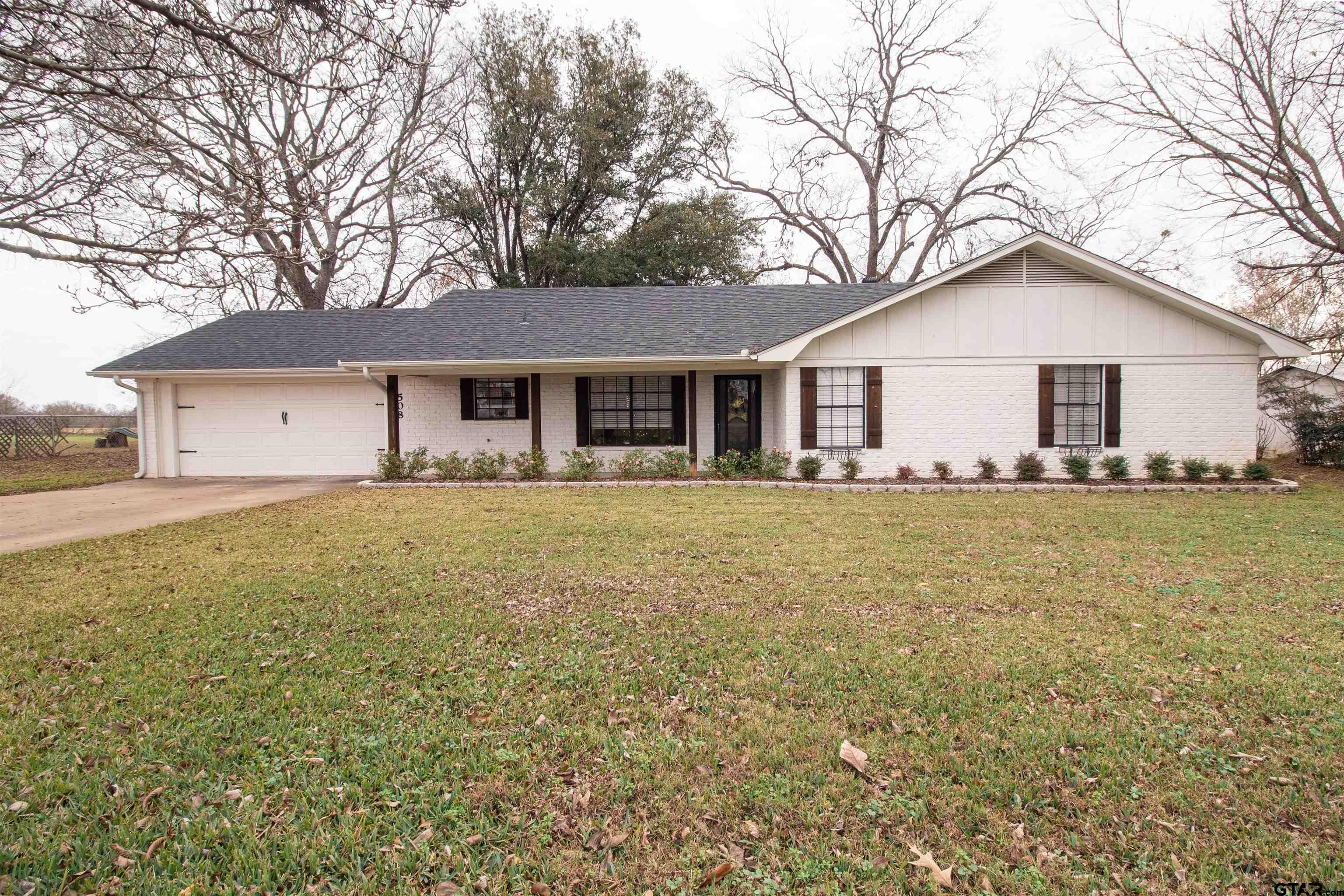 a front view of house with yard and trees around