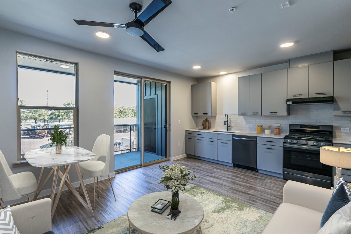 a kitchen with stainless steel appliances granite countertop wooden floor sink stove dining table and chairs