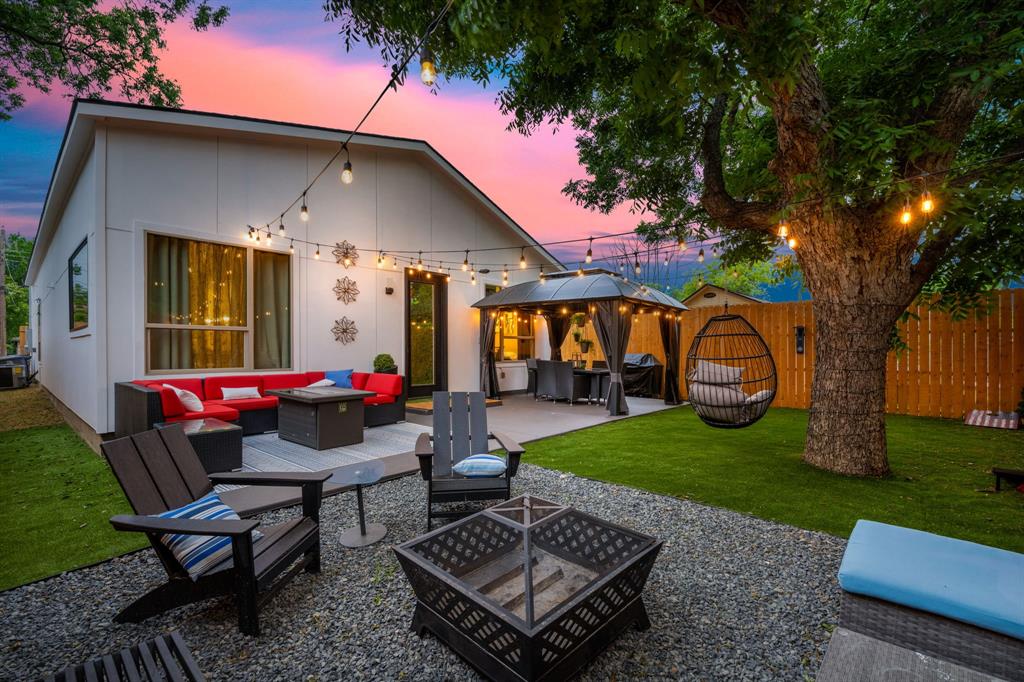 a view of a backyard with table and chairs potted plants and a large tree